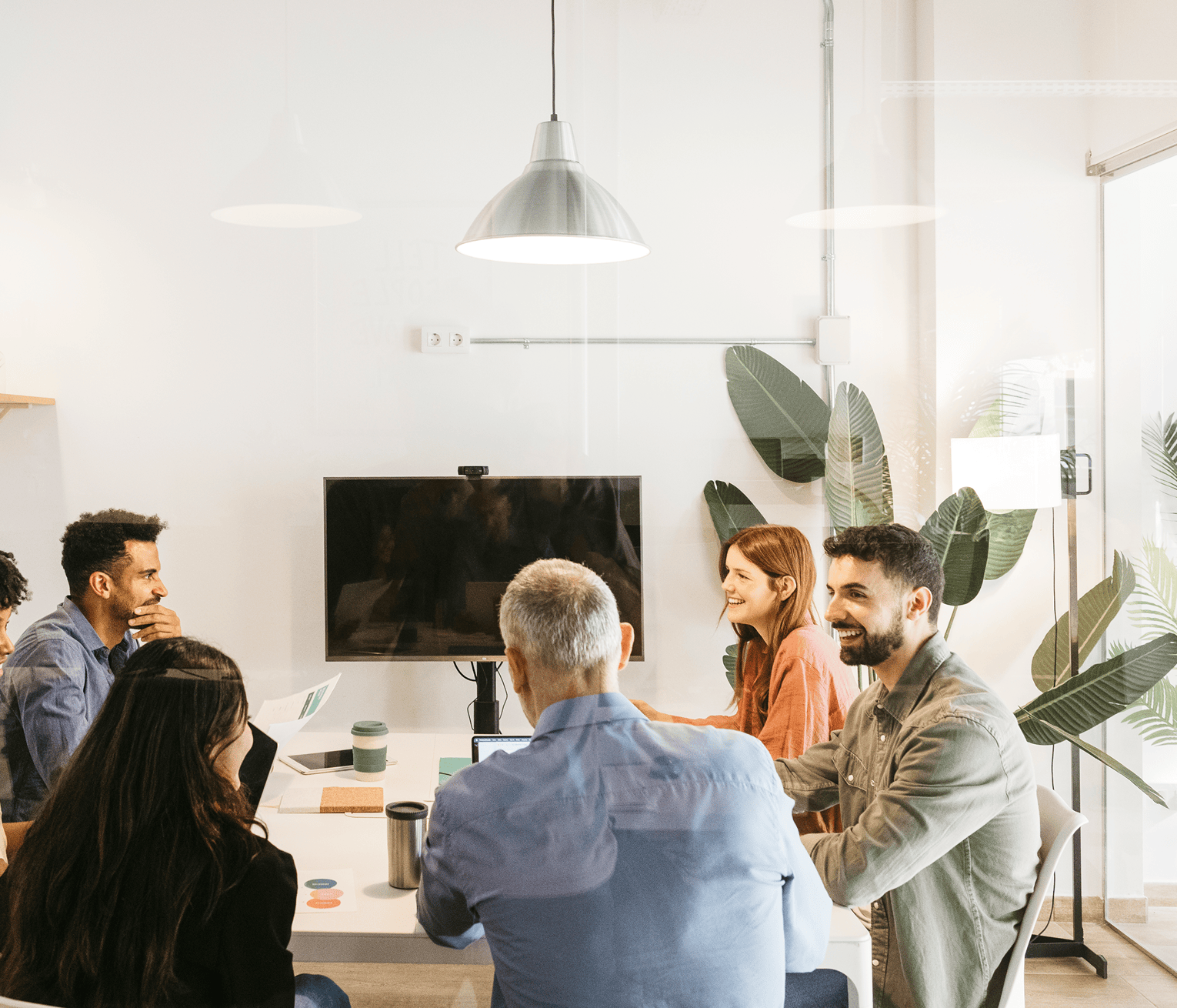 A group of colleagues collaborating around a meeting table in a bright modern office.