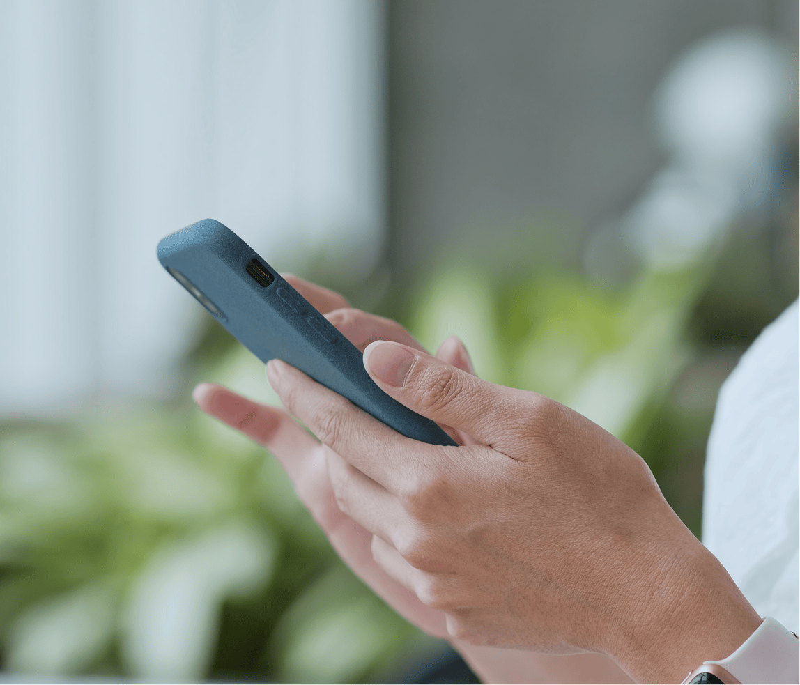 Close-up of hands holding a smartphone in a modern office setting.