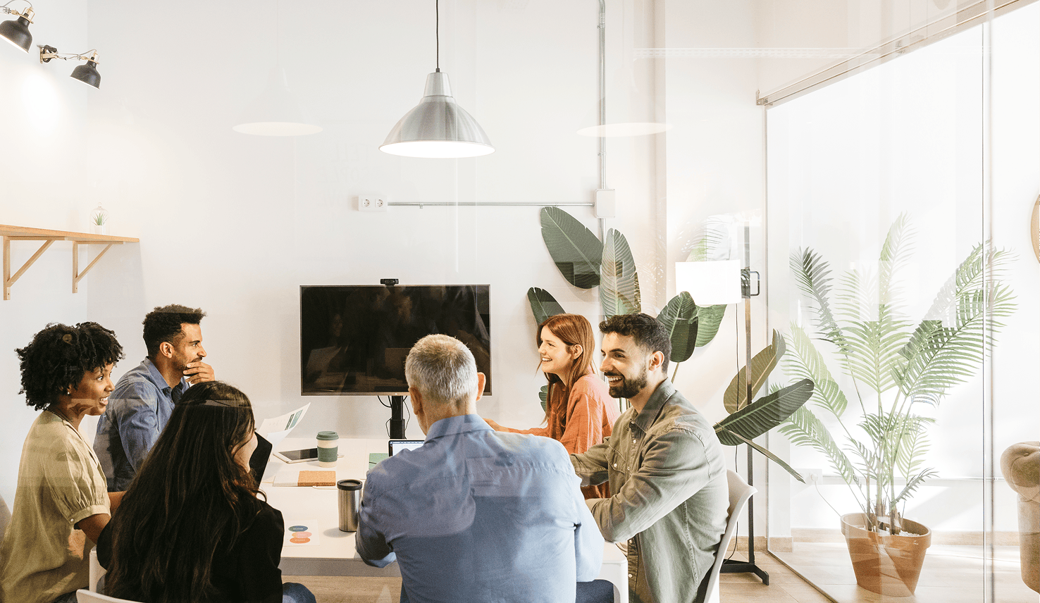 A group of colleagues collaborating around a meeting table in a bright modern office.